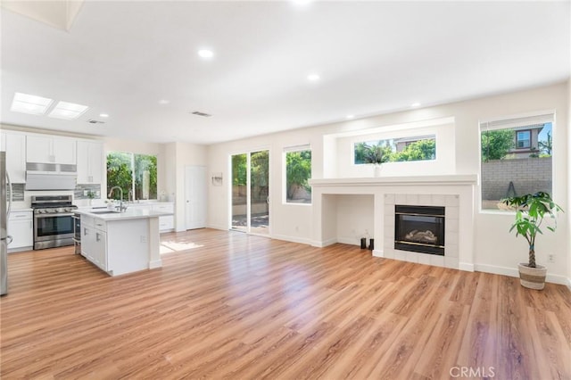 149 E Saint Andrews St, Ontario, CA 91761 - kitchen with gas stove, light countertops, open floor plan, light wood finished floors, and a tile fireplace