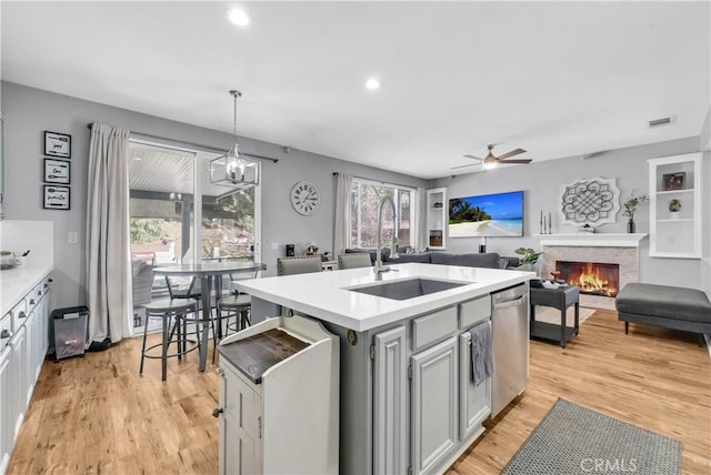 31164 Twilight Vista Dr, Menifee, CA 92584 - kitchen featuring stainless steel dishwasher, light wood finished floors, a ceiling fan, a fireplace, and light countertops