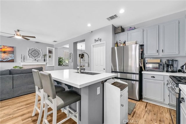 31164 Twilight Vista Dr, Menifee, CA 92584 - kitchen with appliances with stainless steel finishes, ceiling fan, a center island with sink, light countertops, and light wood finished floors
