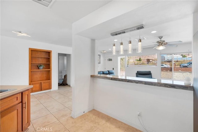23859 S Rd, Apple Valley, CA 92307 - kitchen with ceiling fan, brown cabinets, light tile patterned floors, decorative light fixtures, and light countertops