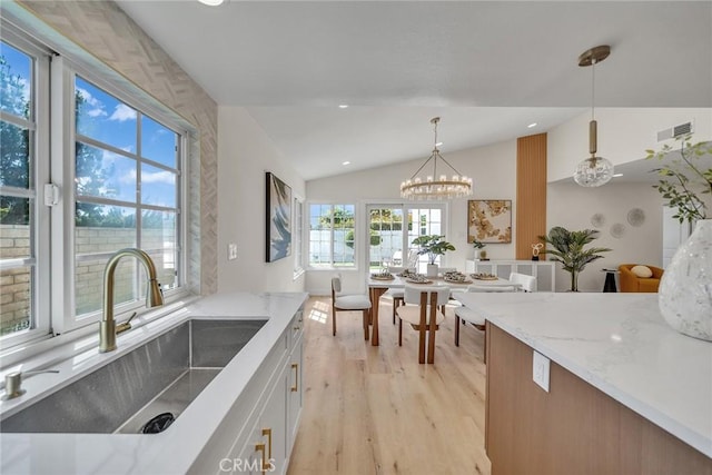 14181 Moore Ct, Irvine, CA 92606 - kitchen featuring light wood-style floors, vaulted ceiling, light stone countertops, decorative light fixtures, and white cabinets