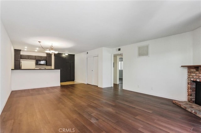 8544 Independence Ave Unit 102, Canoga Park, CA 91304 - unfurnished living room with a chandelier, a brick fireplace, and dark wood-style flooring