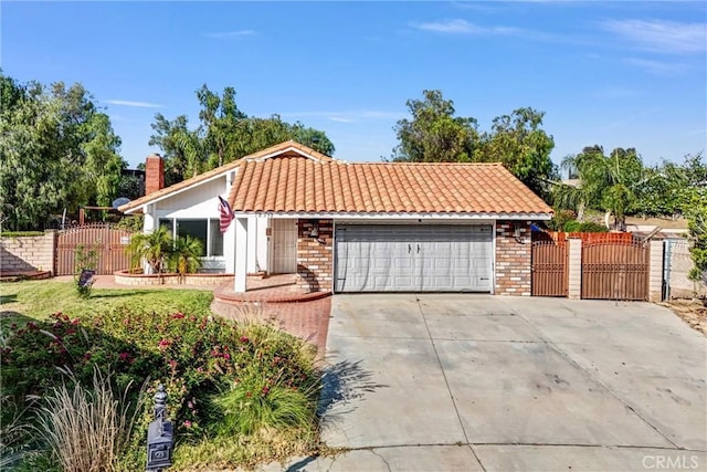 12312 Marmont Pl, Moreno Valley, CA 92557 - view of front of property with a gate, a garage, a tile roof, driveway, and brick siding