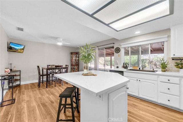 12312 Marmont Pl, Moreno Valley, CA 92557 - kitchen with a center island, white cabinets, a kitchen bar, light countertops, and light wood-type flooring