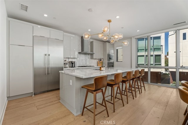 3306 Via Oporto, Newport Beach, CA 92663 - kitchen featuring wall chimney range hood, stainless steel appliances, light wood-style flooring, a chandelier, and pendant lighting