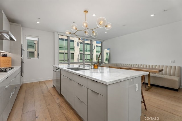 3306 Via Oporto, Newport Beach, CA 92663 - kitchen featuring modern cabinets, light wood-style flooring, a chandelier, a center island with sink, and wall chimney range hood