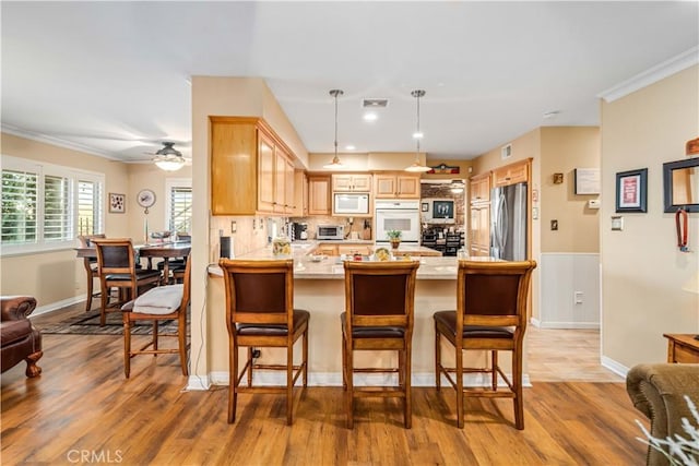 35870 Tierra Subida Ave, Palmdale, CA 93551 - kitchen featuring white appliances, a peninsula, crown molding, light wood-style flooring, and light brown cabinetry