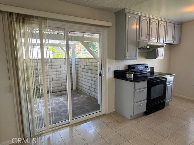 1353 E Fairgrove Ave Unit 293, West Covina, CA 91792 - kitchen with black range with electric cooktop, under cabinet range hood, dark countertops, plenty of natural light, and a textured ceiling