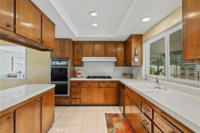 3186 N Hartman St, Orange, CA 92865 - kitchen featuring under cabinet range hood, brown cabinetry, a raised ceiling, and recessed lighting