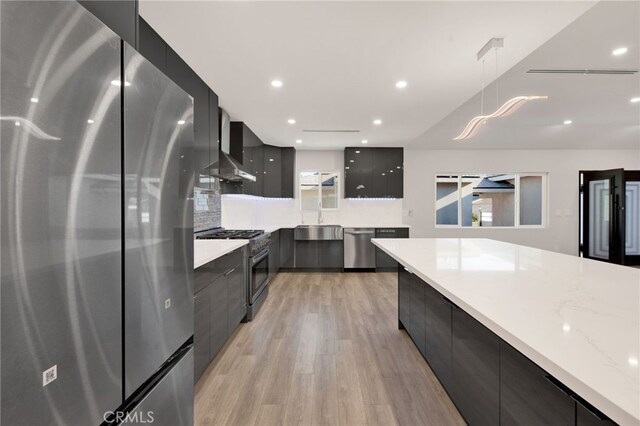 14625 Runnymede St, Van Nuys, CA 91405 - kitchen featuring stainless steel appliances, modern cabinets, wall chimney range hood, dark cabinets, and light wood finished floors