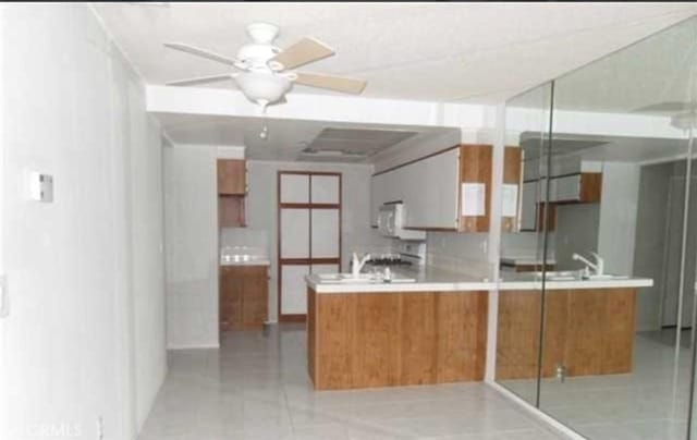 44460 15th St E Unit 3, Lancaster, CA 93535 - kitchen with brown cabinetry, ceiling fan, light tile patterned floors, and light countertops