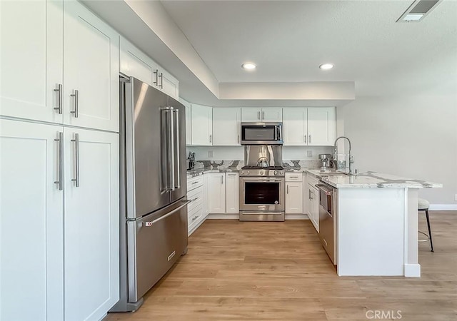 19237 Index St Unit 5, Porter Ranch, CA 91326 - kitchen featuring high quality appliances, a peninsula, white cabinetry, light wood finished floors, and recessed lighting