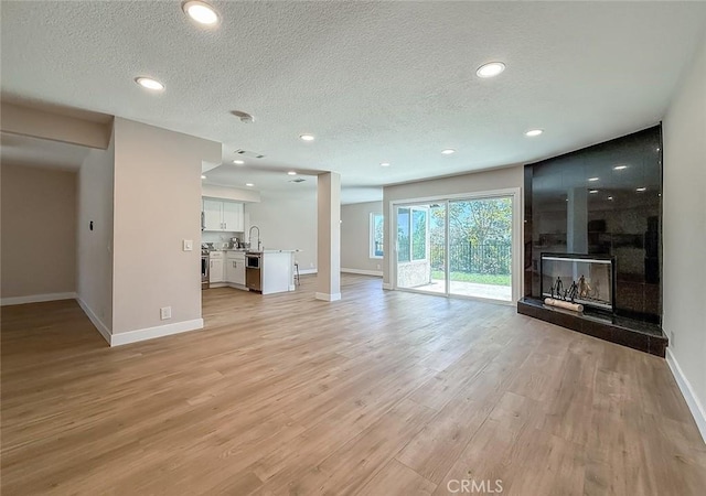 19237 Index St Unit 5, Porter Ranch, CA 91326 - unfurnished living room with a textured ceiling, light wood-style floors, a fireplace, and recessed lighting