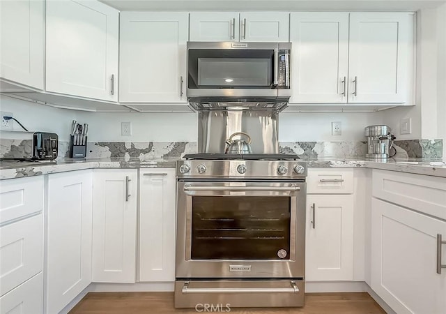19237 Index St Unit 5, Porter Ranch, CA 91326 - kitchen featuring appliances with stainless steel finishes, white cabinets, light stone countertops, and light wood-style flooring