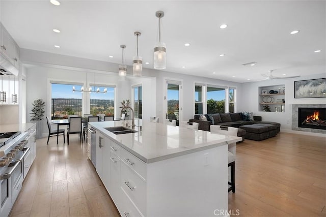 27705 Homestead Rd, Laguna Niguel, CA 92677 - kitchen featuring recessed lighting, a warm lit fireplace, light wood-style flooring, a large island with sink, and white cabinets