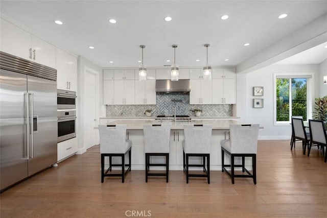 27705 Homestead Rd, Laguna Niguel, CA 92677 - kitchen with stainless steel built in refrigerator, under cabinet range hood, tasteful backsplash, light countertops, and a breakfast bar area