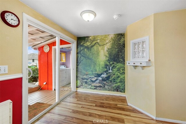 1780 Paso Robles St, Oceano, CA 93445 - doorway to outside with wood finished floors, washing machine and clothes dryer, and an accent wall