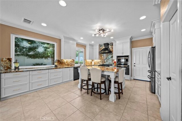 32409 Favara Dr, Temecula, CA 92592 - kitchen with decorative backsplash, appliances with stainless steel finishes, white cabinetry, light stone counters, and wall chimney range hood