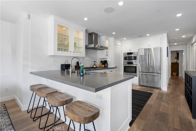 112 30th St, Newport Beach, CA 92663 - kitchen with appliances with stainless steel finishes, wall chimney range hood, a peninsula, dark wood-type flooring, and glass insert cabinets