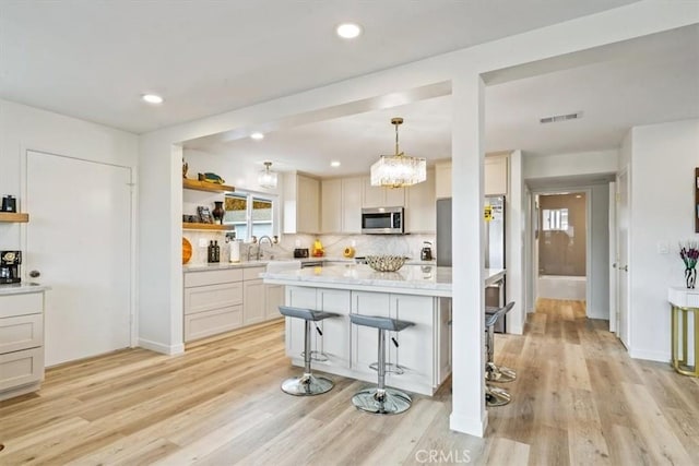 31 N 3rd St, Cayucos, CA 93430 - kitchen with stainless steel microwave, open shelves, backsplash, light wood-style flooring, and recessed lighting