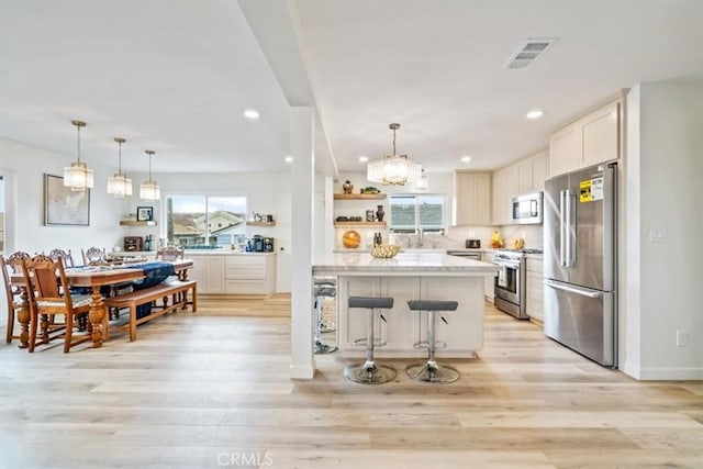 31 N 3rd St, Cayucos, CA 93430 - kitchen with stainless steel appliances, a breakfast bar area, a chandelier, open shelves, and light wood-style flooring