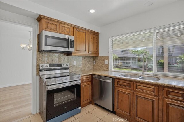 14652 Devonshire Ave, Tustin, CA 92780 - kitchen with stainless steel appliances, brown cabinetry, backsplash, light stone counters, and recessed lighting