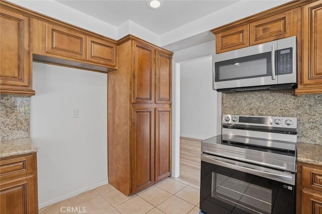 14652 Devonshire Ave, Tustin, CA 92780 - kitchen featuring stainless steel appliances, brown cabinets, and light stone countertops