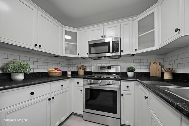 190 Avenida Descanso Unit I, Oceanside, CA 92057 - kitchen featuring appliances with stainless steel finishes, white cabinets, tasteful backsplash, glass insert cabinets, and dark stone countertops
