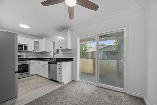 190 Avenida Descanso Unit I, Oceanside, CA 92057 - kitchen with stainless steel appliances, crown molding, dark countertops, white cabinets, and backsplash