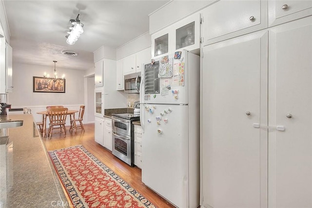 1242 2nd Pl, Calimesa, CA 92320 - kitchen with appliances with stainless steel finishes, white cabinetry, light wood-style flooring, a chandelier, and glass insert cabinets
