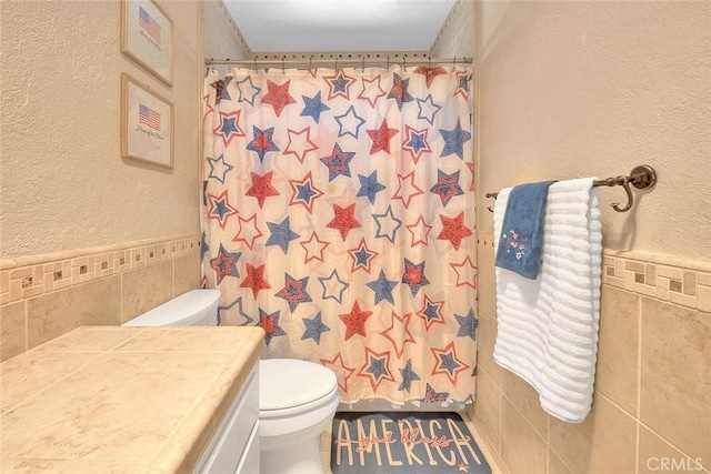 1242 2nd Pl, Calimesa, CA 92320 - bathroom featuring tile walls, vanity, a textured wall, curtained shower, and a wainscoted wall