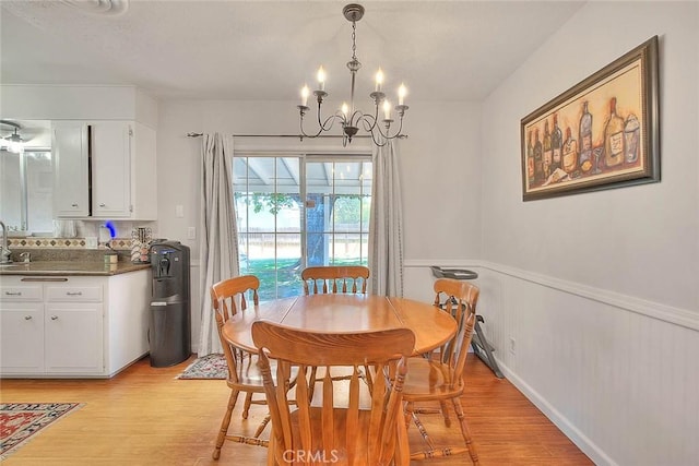 1242 2nd Pl, Calimesa, CA 92320 - dining area featuring a chandelier, light wood-style floors, and a wainscoted wall