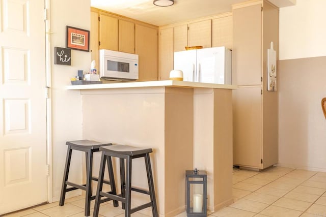 1000 Rodeo Dr Unit 515, Imperial, CA 92251 - kitchen featuring white appliances, light tile patterned floors, a breakfast bar area, and light countertops