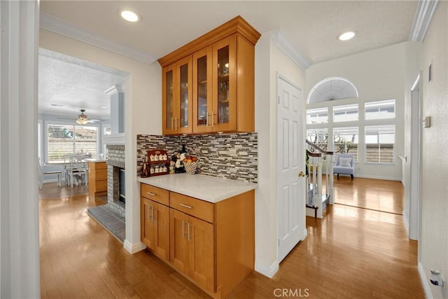 4350 Bennington Ct, Chino, CA 91710 - bar area featuring backsplash, light wood finished floors, a fireplace, ornamental molding, and a ceiling fan