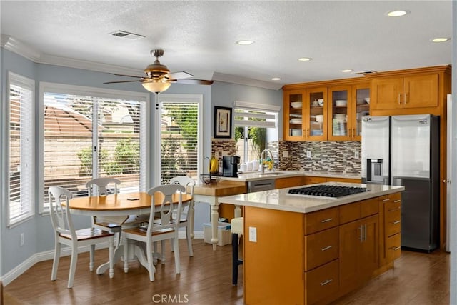 4350 Bennington Ct, Chino, CA 91710 - kitchen with appliances with stainless steel finishes, decorative backsplash, ceiling fan, crown molding, and light countertops