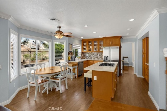 4350 Bennington Ct, Chino, CA 91710 - kitchen with stainless steel appliances, brown cabinets, decorative backsplash, glass insert cabinets, and wood finished floors