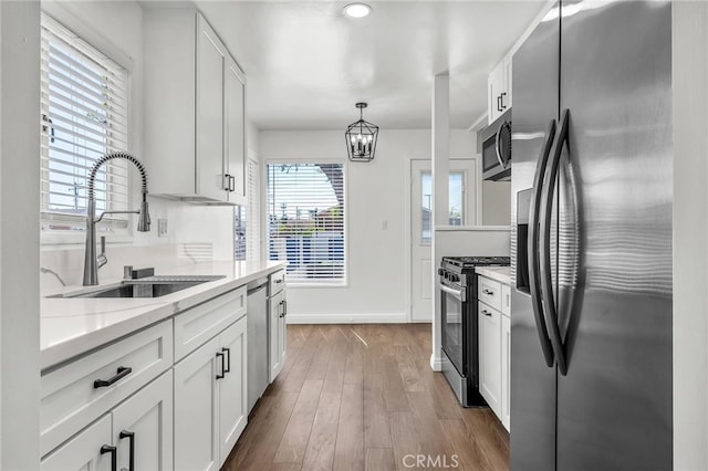 835 E 222nd St, Carson, CA 90745 - kitchen featuring stainless steel appliances, white cabinetry, wood finished floors, a chandelier, and decorative light fixtures