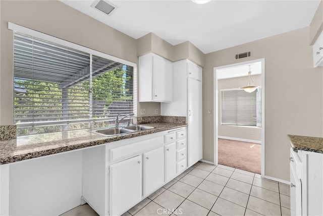 1407 Opal St, Corona, CA 92882 - kitchen with healthy amount of natural light, white cabinetry, light tile patterned floors, and dark stone countertops