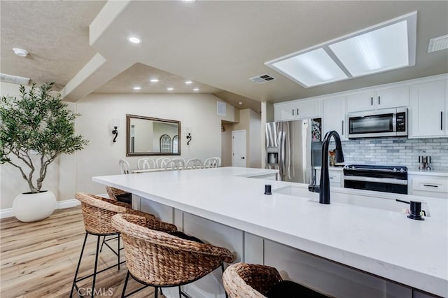 7434 Paisley Ave, Hesperia, CA 92345 - kitchen featuring appliances with stainless steel finishes, light wood-style flooring, recessed lighting, a breakfast bar, and backsplash