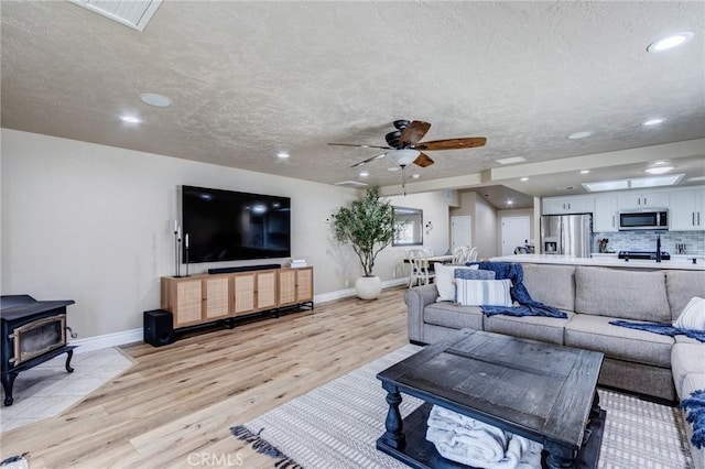 7434 Paisley Ave, Hesperia, CA 92345 - living area with light wood-style flooring, a wood stove, a ceiling fan, a textured ceiling, and recessed lighting