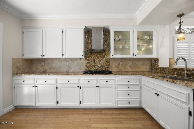 7748 Paso Robles St, Ventura, CA 93004 - kitchen with wall chimney range hood, white cabinets, ornamental molding, decorative backsplash, and stone counters