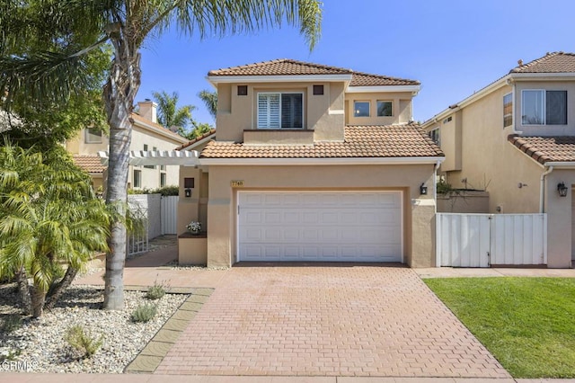 7748 Paso Robles St, Ventura, CA 93004 - mediterranean / spanish house featuring stucco siding, a tiled roof, decorative driveway, and a gate