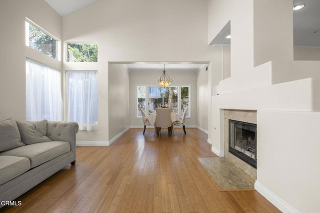 7748 Paso Robles St, Ventura, CA 93004 - living area featuring high vaulted ceiling, light wood-style flooring, a chandelier, and a tiled fireplace