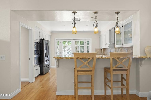 7748 Paso Robles St, Ventura, CA 93004 - kitchen featuring appliances with stainless steel finishes, a peninsula, white cabinets, light wood finished floors, and ornamental molding
