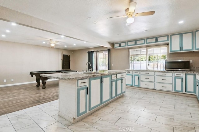 15722 Inyo St, Victorville, CA 92395 - kitchen with light marble finish flooring, ceiling fan, recessed lighting, stainless steel microwave, and an island with sink