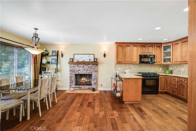 21460 Arapahoe Trl, Chatsworth, CA 91311 - kitchen with black appliances, brown cabinetry, wood finished floors, tasteful backsplash, and glass insert cabinets