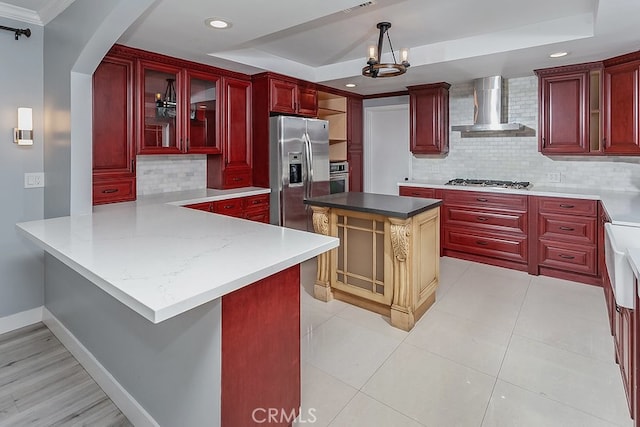 22017 Bryant St, West Hills, CA 91304 - kitchen featuring wall chimney exhaust hood, reddish brown cabinets, appliances with stainless steel finishes, a tray ceiling, and decorative backsplash