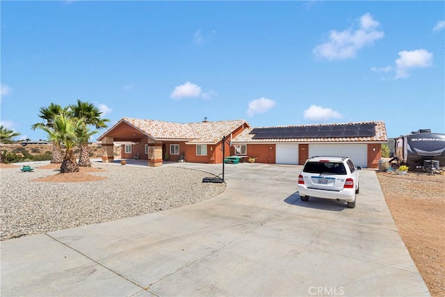 9512 Mesquite St, Phelan, CA 92371 - ranch-style house featuring a garage, roof mounted solar panels, concrete driveway, and a tiled roof