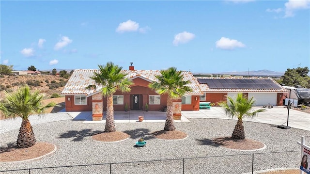 9512 Mesquite St, Phelan, CA 92371 - view of front of home featuring roof mounted solar panels, a tiled roof, driveway, a chimney, and stucco siding