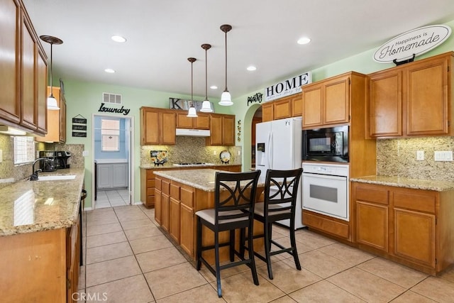 27597 Lafayette Way, Moreno Valley, CA 92555 - kitchen with white appliances, under cabinet range hood, decorative backsplash, light tile patterned floors, and recessed lighting
